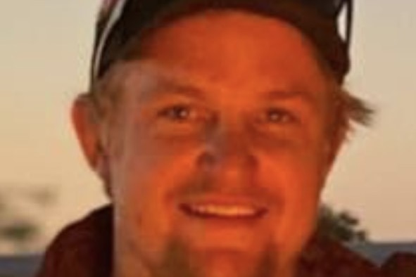 A young man, wearing a baseball cap, smiling.