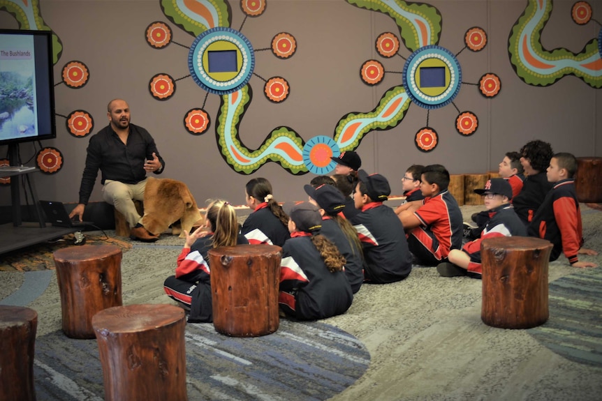 A group of kids sit on the floor.