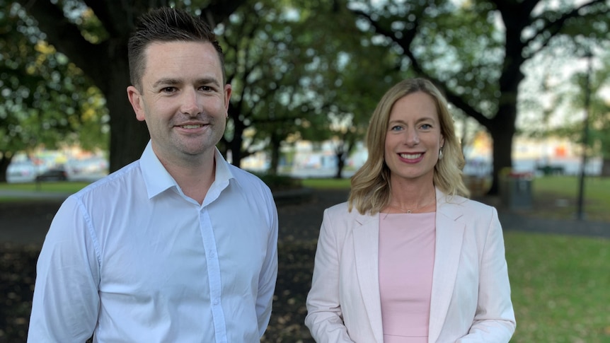 A man and a woman stand next to each other in a park