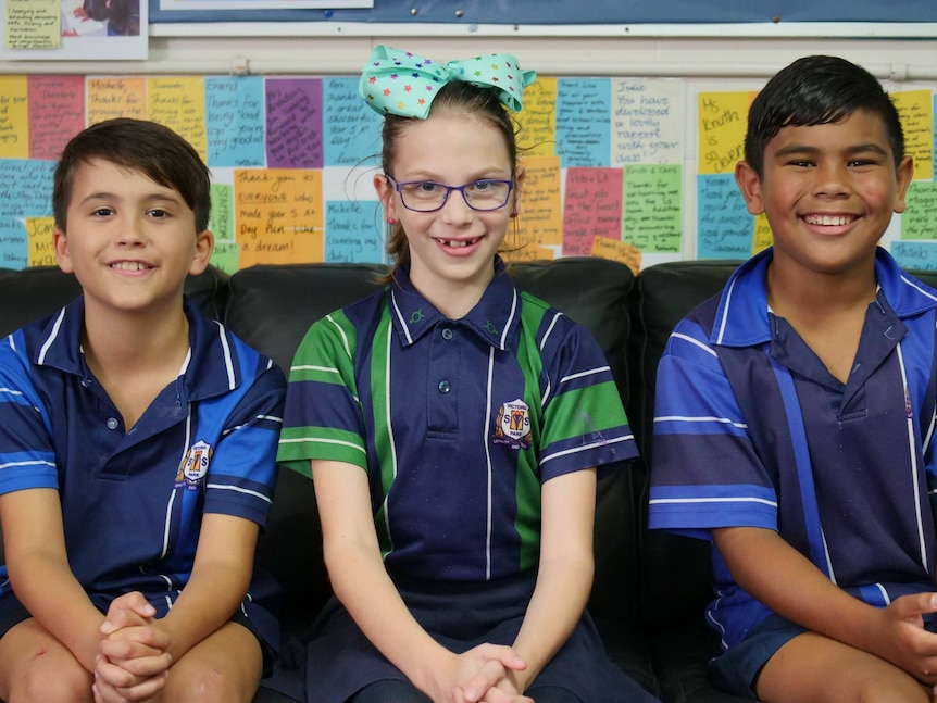 Three primary school students sitting together.