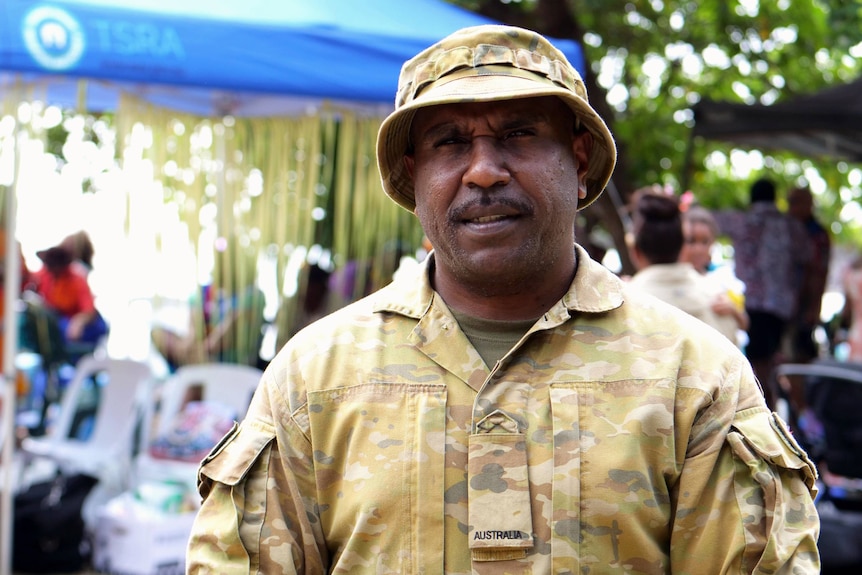 Torres Strait Islander man wearing army greens smiles at the camera.
