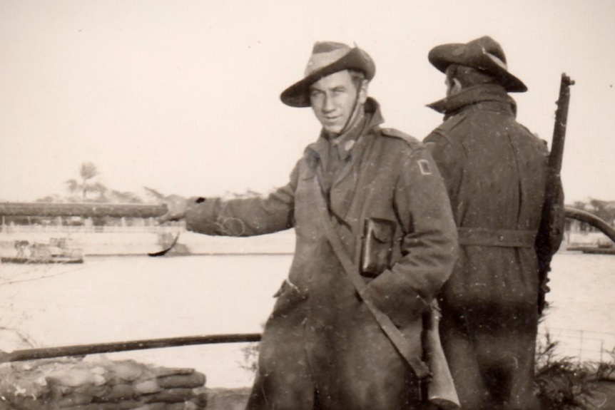 Two men in 1940s Australian Army uniform standing next to the river Nile in Egypt, one man is looking at the camera.