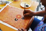 An Indigenous prisoner practising dot painting an Indigenous weekly art classes.