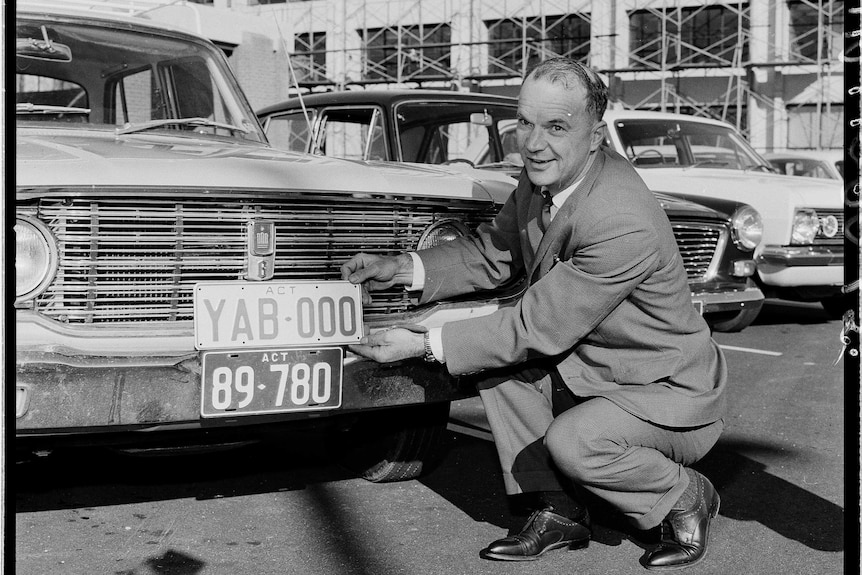 The recipient of Canberra's first Y number plate poses with it beside his car.