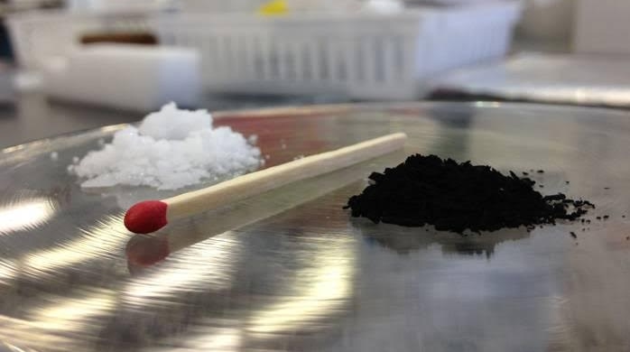 A pile of naphthalene (left) separated by a match from a pile of carbon material (right)