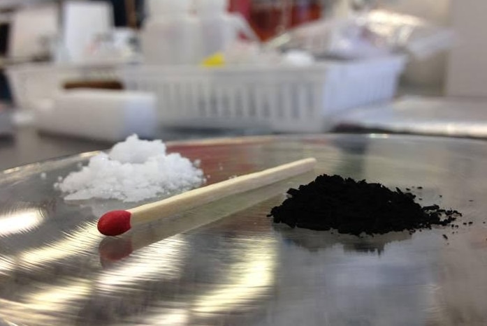 A pile of naphthalene (left) separated by a match from a pile of carbon material (right)