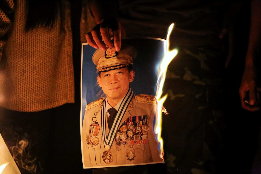 People burn a portrait of Army chief General Min Aung Hlaing