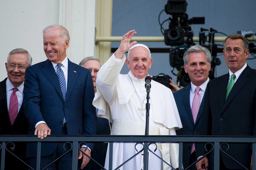 US politicians, including President Biden, with Pope Francis, who is waving, at the US Capitol building in 2015.