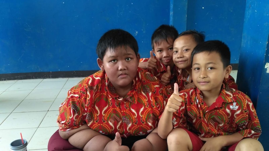 Three kids showing their thumbs to camera