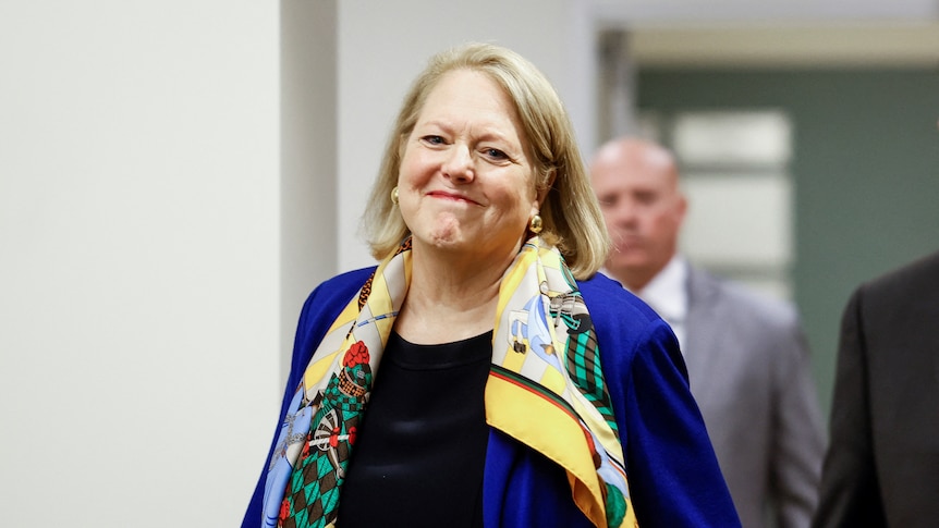 Virginia Thomas is walking down a hallway and smiling with her mouth closed. 
