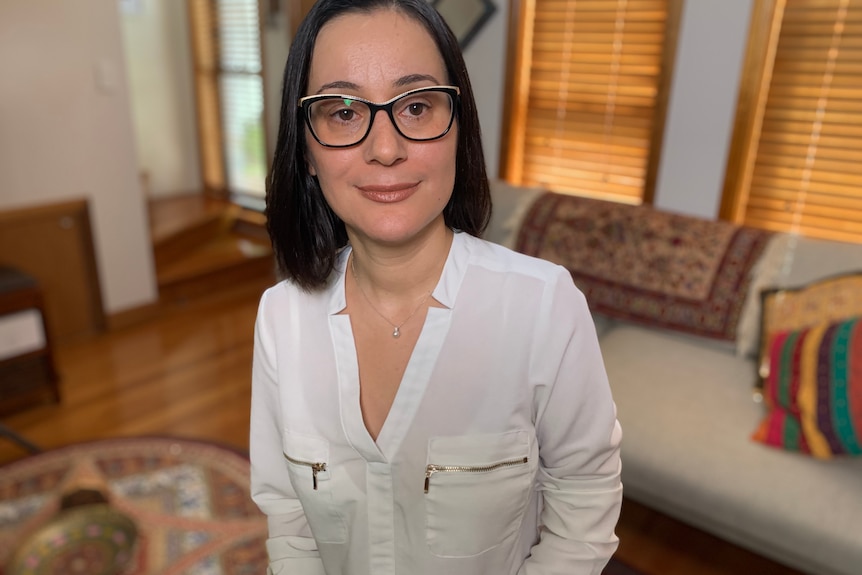 Woman wearing a white shirt standing in a living room.