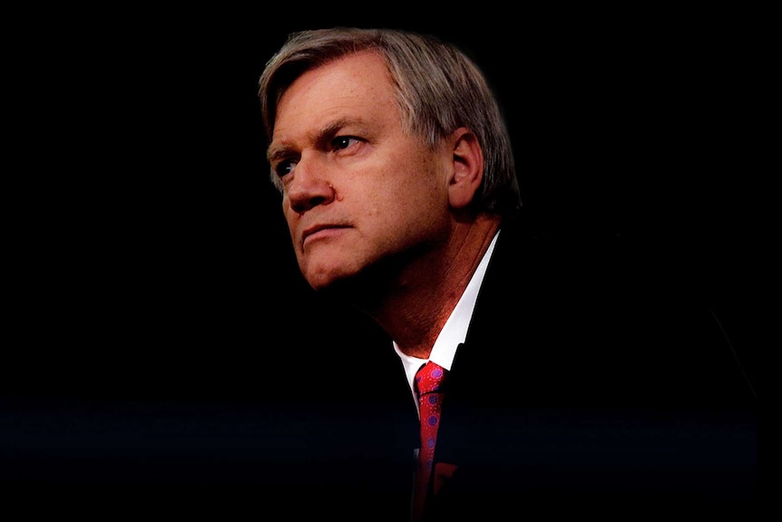 Andrew Bolt, wearing a suit and red tie, glances sideways. The background is dark black.