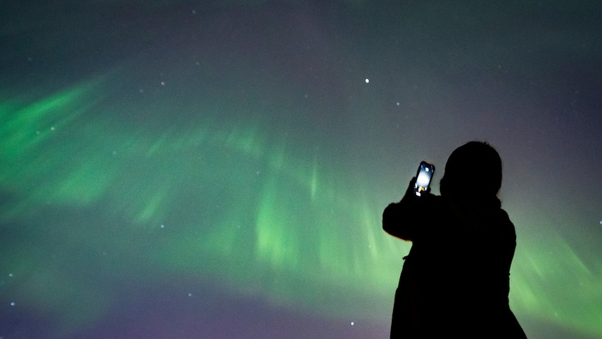 A person takes a photo of the aurora borealis in Vancouver. 