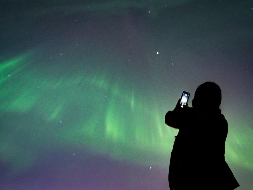 A person takes a photo of the aurora borealis in Vancouver. 