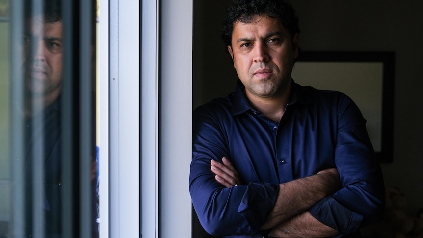 a man leaning against the wall next to a window