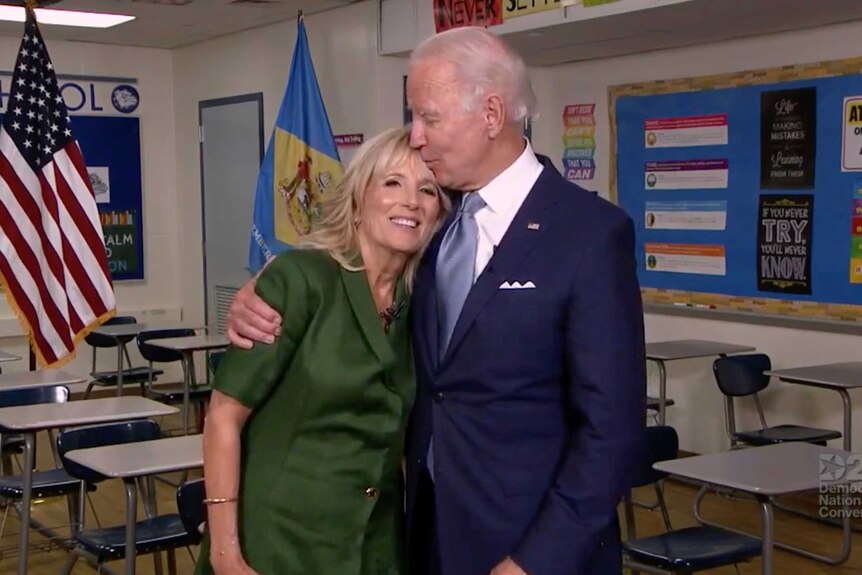 Joe Biden hugging Jill Biden and kissing her forehead in a school classroom