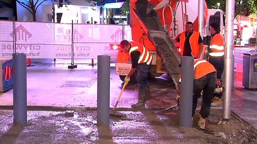 A construction worker installing new security bollards in Bourke St Mall.