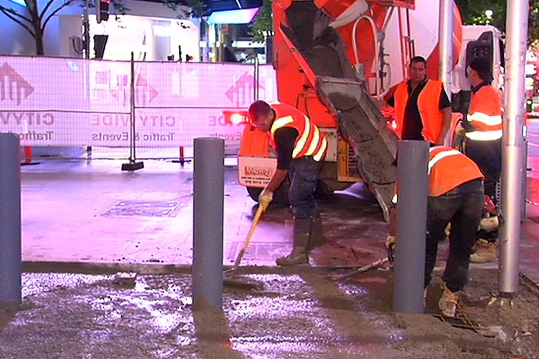A construction worker installing new security bollards in Bourke St Mall.