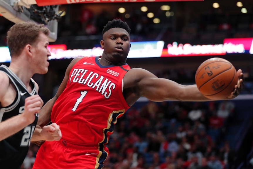 Zion Williamson reaches for the basketball in his NBA debut.