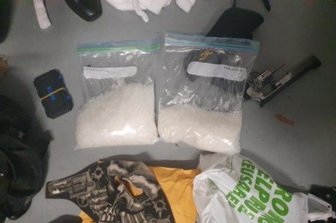 Two plastic bags filled with white crystal meth surrounded by drug paraphernalia and a hand gun