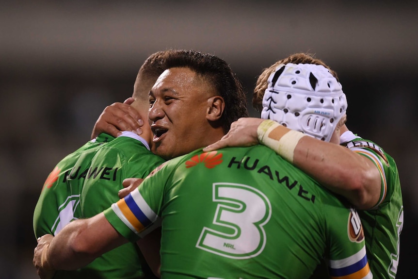 Four Canberra Raiders players embrace as they celebrate a try against the Bulldogs.