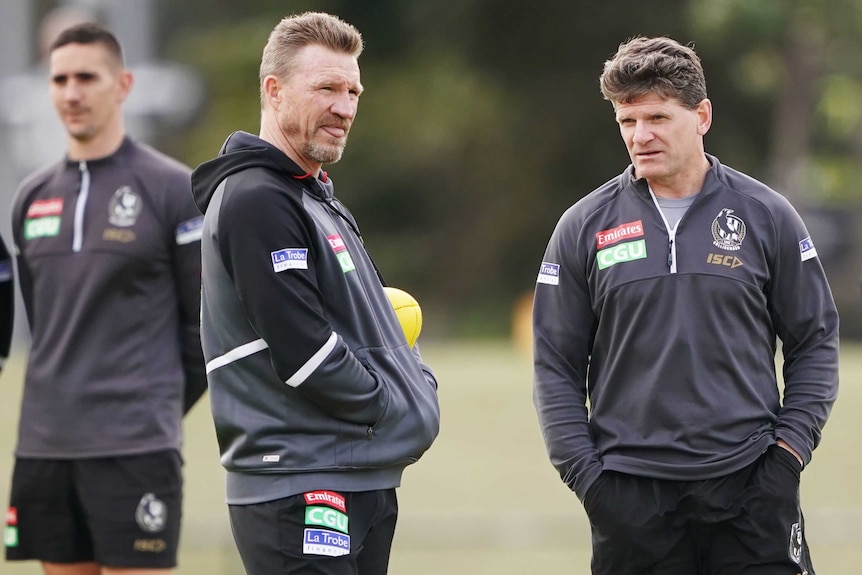 Two Collingwood AFL coaches speak to each other at a Magpies training session.