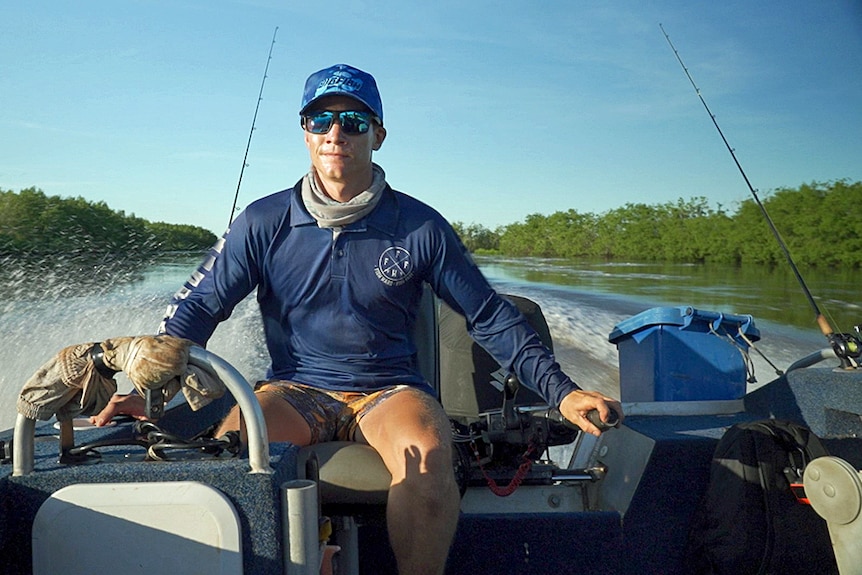 A man drives a boat along a river.