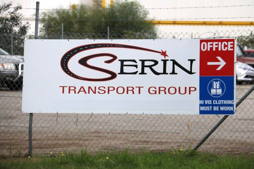 A sign on a fence which reads 'Serin Transport Group'.