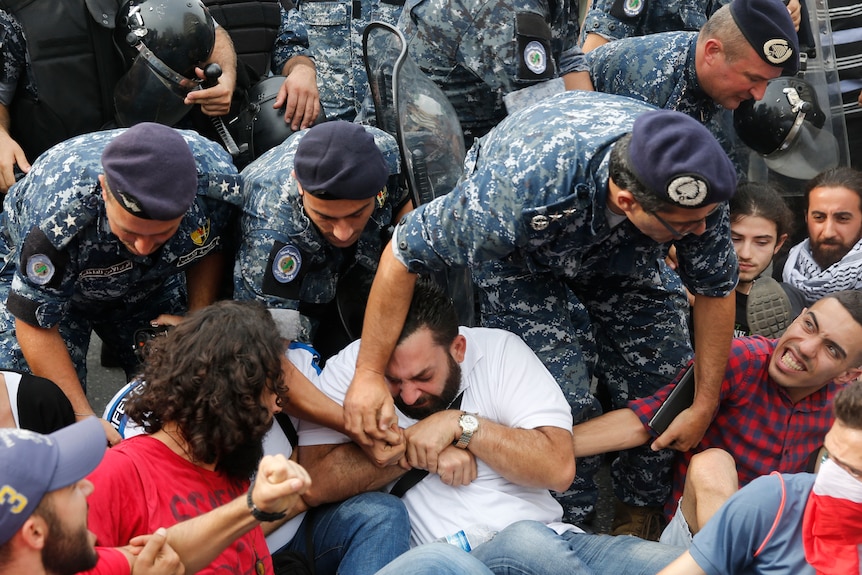 Lebanese riot policemen remove anti-government protesters.