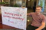 BMX Rider Sam Willoughby holds up a giant 'get well' poster