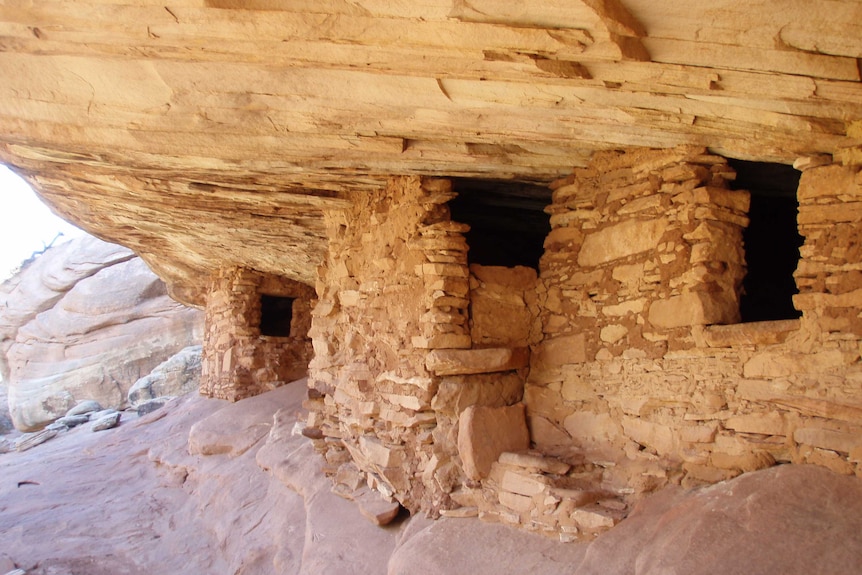 A home is built from sandstone bricks under a canyon shelf.