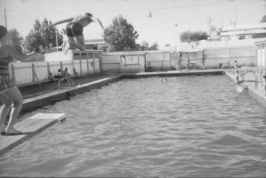 black and white picture of a pool in Gwalia in the late fifties, with a man jumping from the trampoline