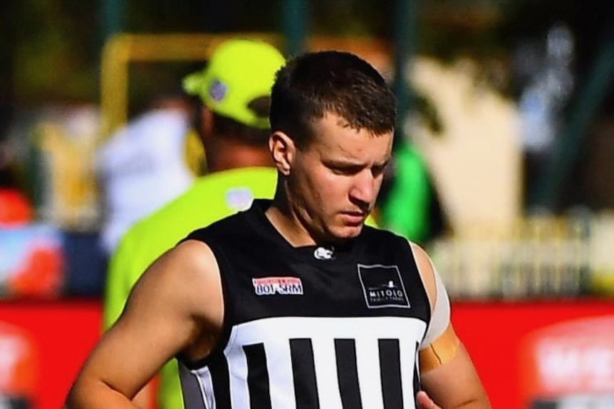 A man in black and white football gear on an oval.