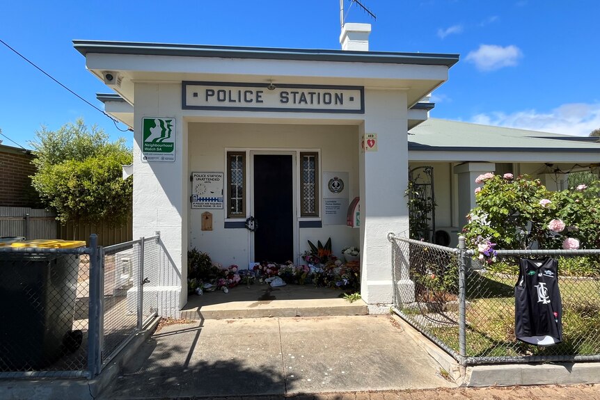 A small police station with flowers and a football jumper in the foyer