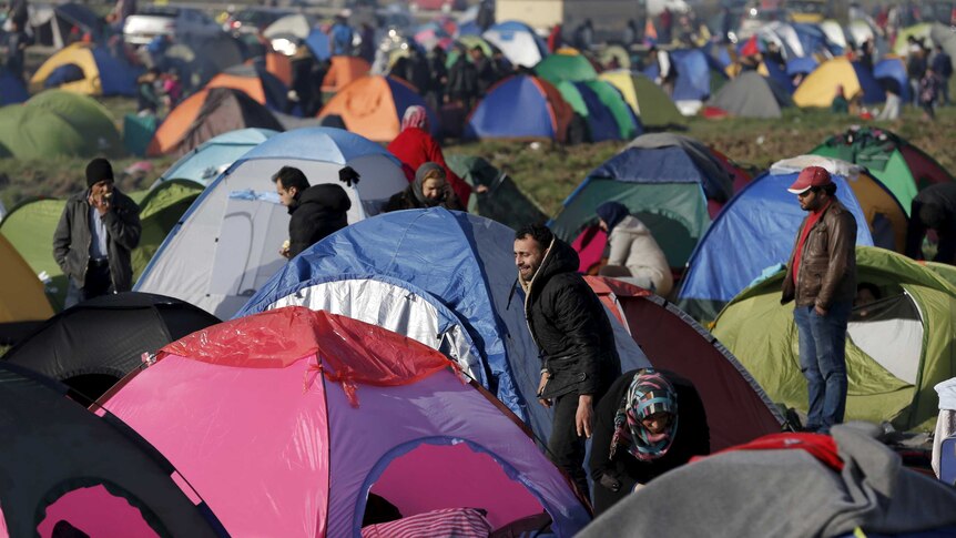 Migrants stand in front of hundreds of tents on the Greek-Macedonian border.