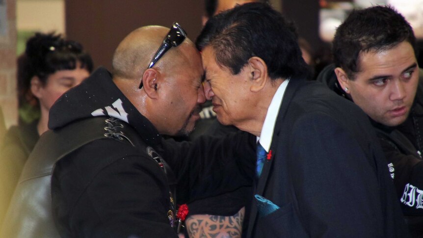 Two men press their noses and foreheads together for a traditional Maori greeting.