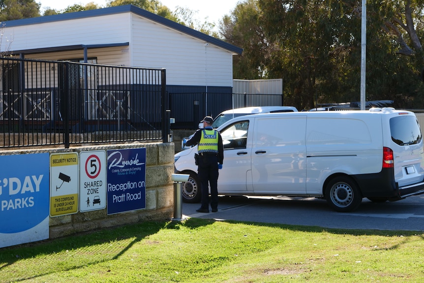A police van at the gateway leading into a caravan park.