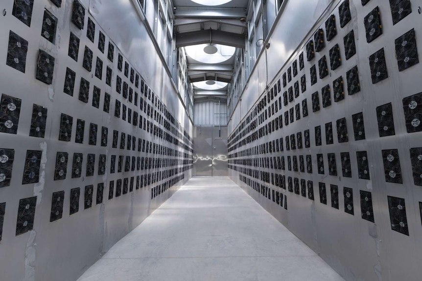 A long grey hallway with walls of computer fans.
