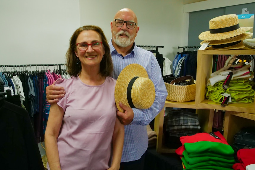 A woman and a man smiling in a charity clothing store wearing new clothes