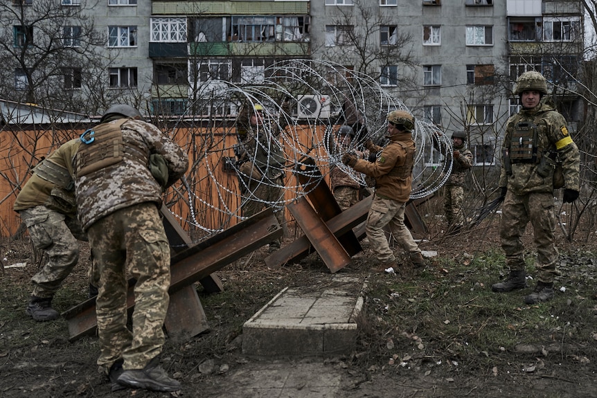Ukrainian soldiers prepare barricade with barbed wire.
