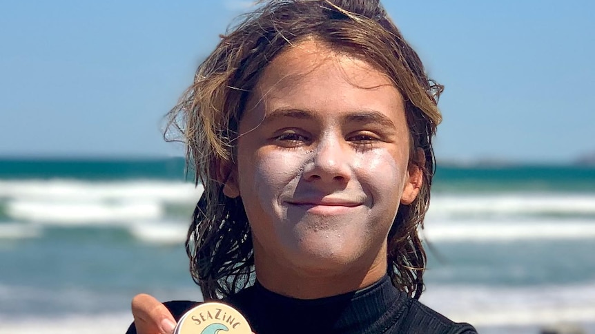 A smiling boy with zinc on his face at the beach.