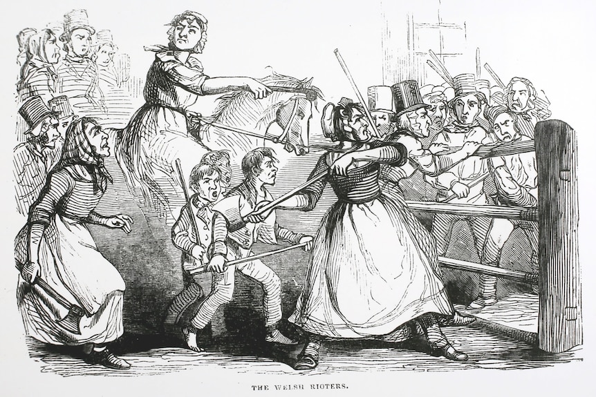 An 1800s illustration of several men dressed as women destroying a fence, as others watch
