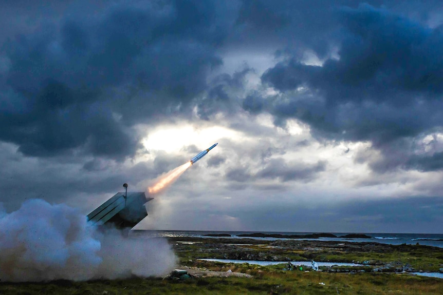 A missile being launched from the ground in front of dark and broody clouds