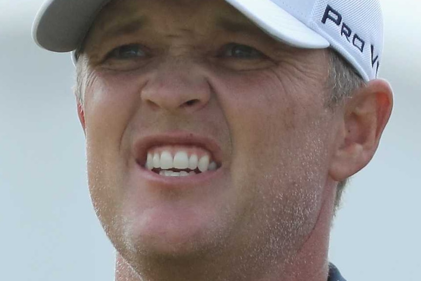 A male golfer grimaces as he watches the progress of a shot during the final round of the Australian Open in Sydney.