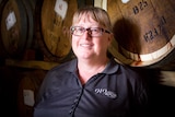 Jenny Semmler stands in front of barrels of wine.