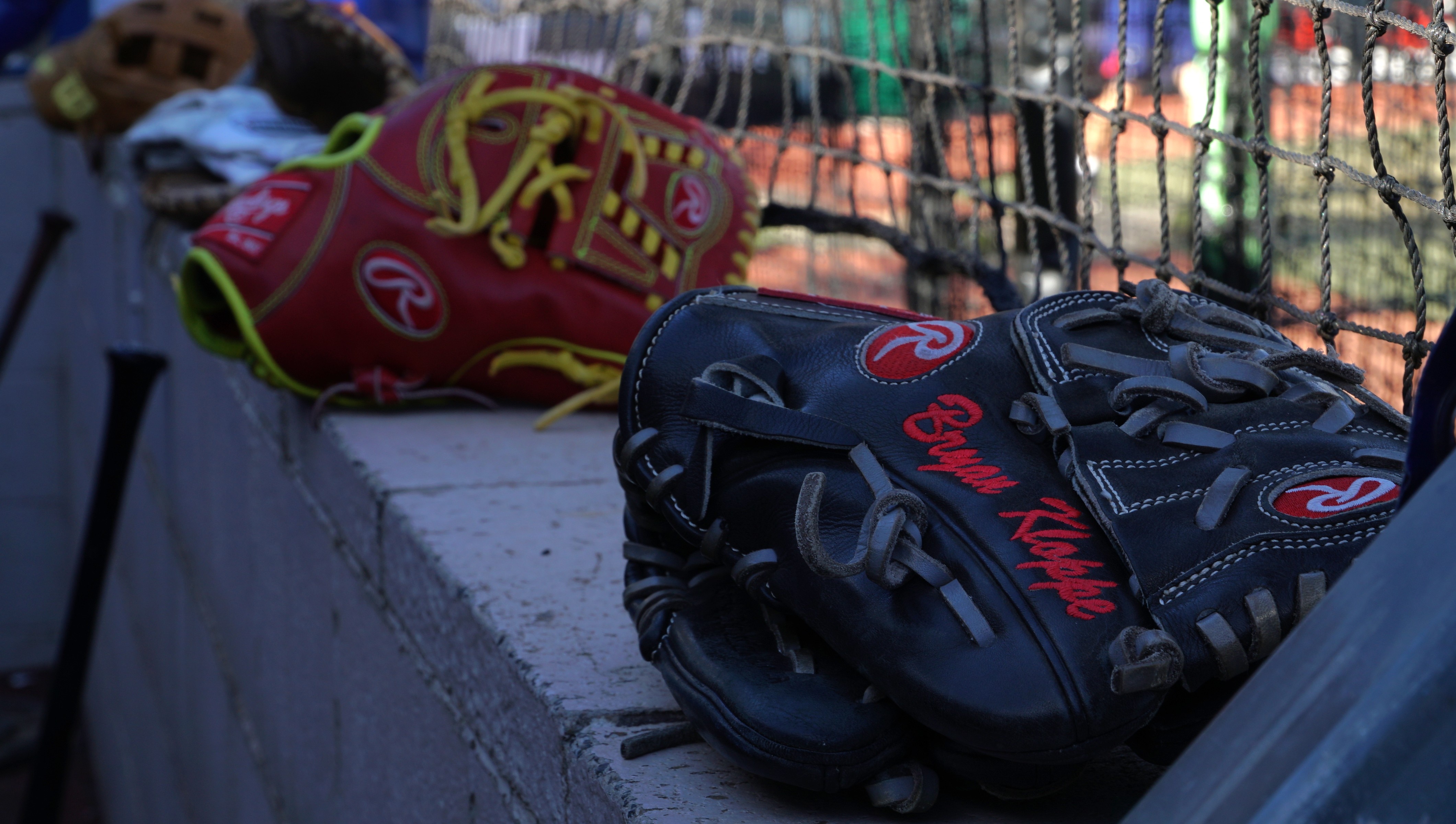 Uma luva de beisebol preta e vermelha está ao lado de um campo de beisebol.