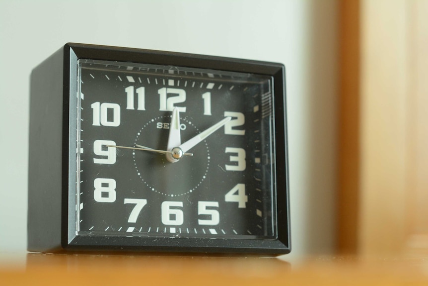 Close-up shot of a small, black Seiko analogue alarm clock with white numbers.