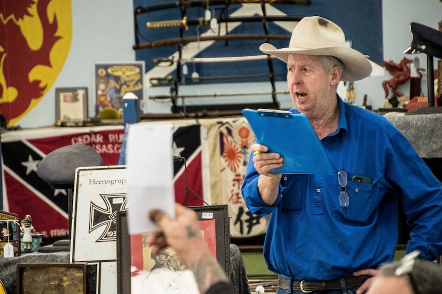 A man holds up his hand to make a bid at a public auction.