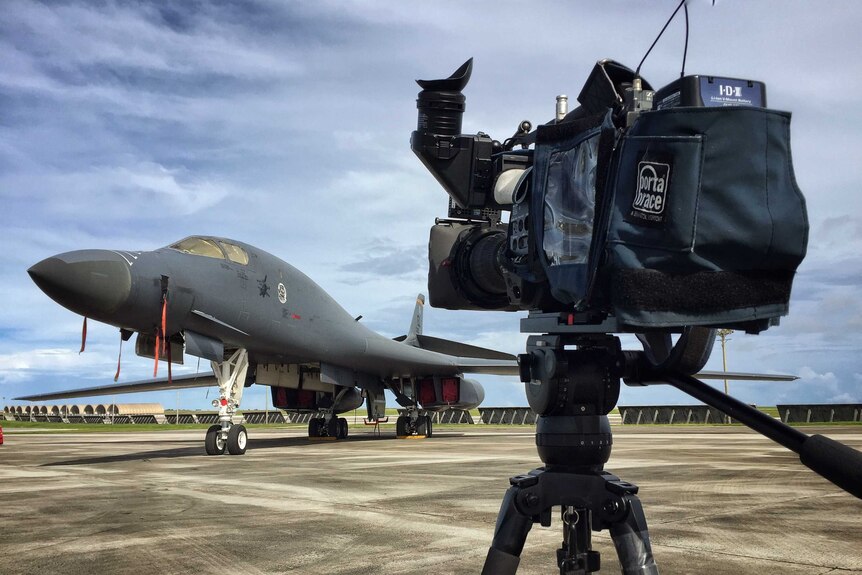ABC News camera on tripod in front of US plane on Guam airbase.