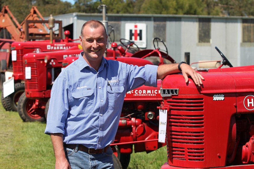 A man stands with a vintage tractor